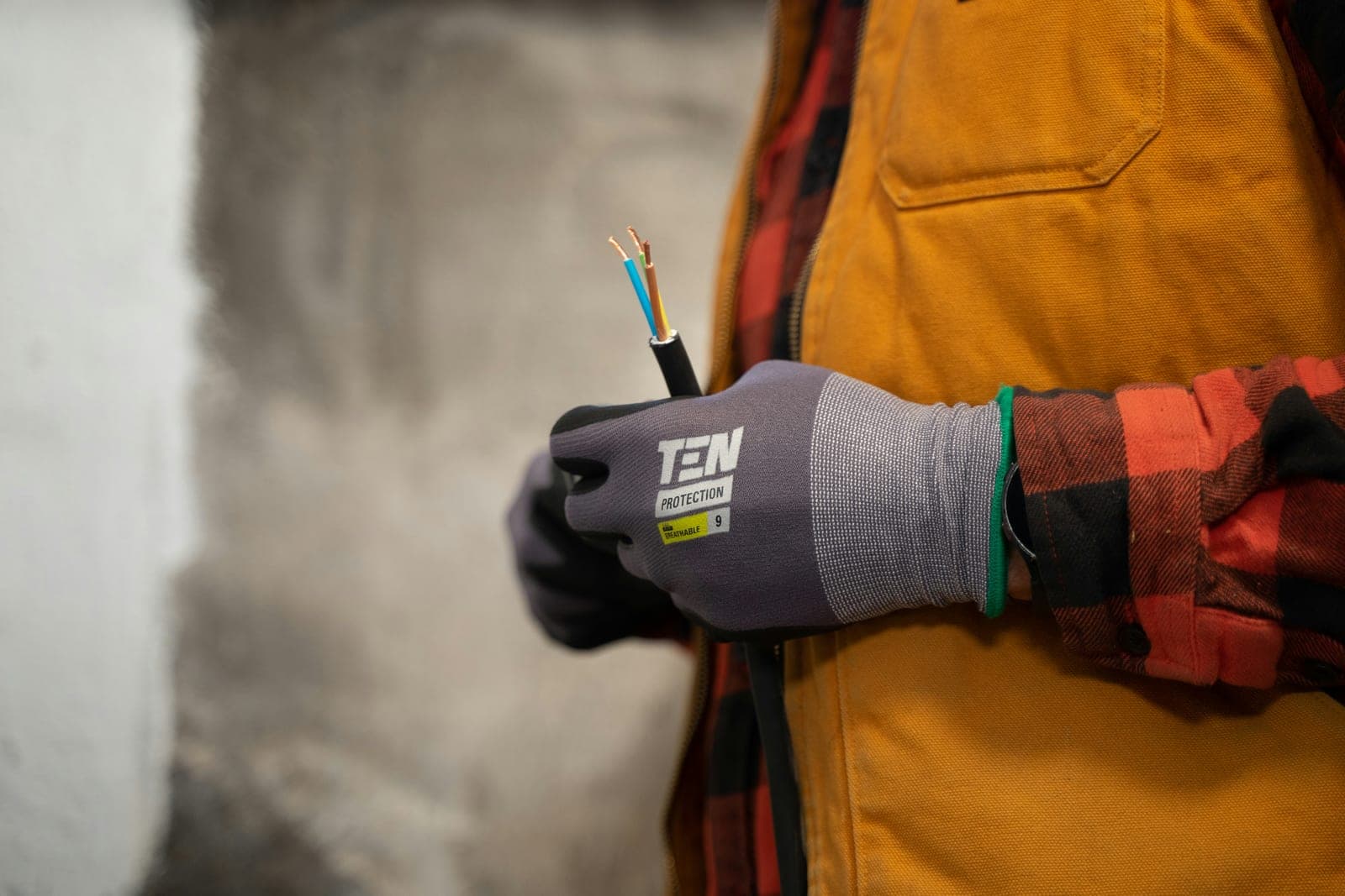 An electrician on site holding a freshly stripped three-core cable
